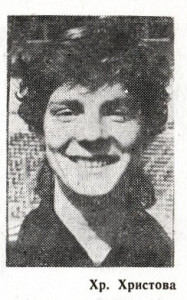 A black and white newspaper photograph of a smiling woman's face. She has curly hair and prominent cheek bones 